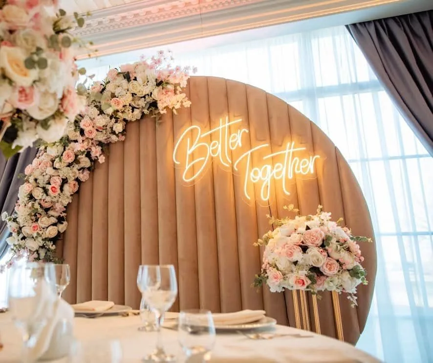 Photo corner cu panou rotund din lemn, neon cu textul Better together și flori roz pudrat